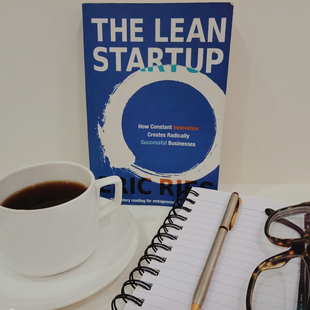 The Lean Startup by Eric Ries. Along with book, coffee, journal, pen and specs are also kept.